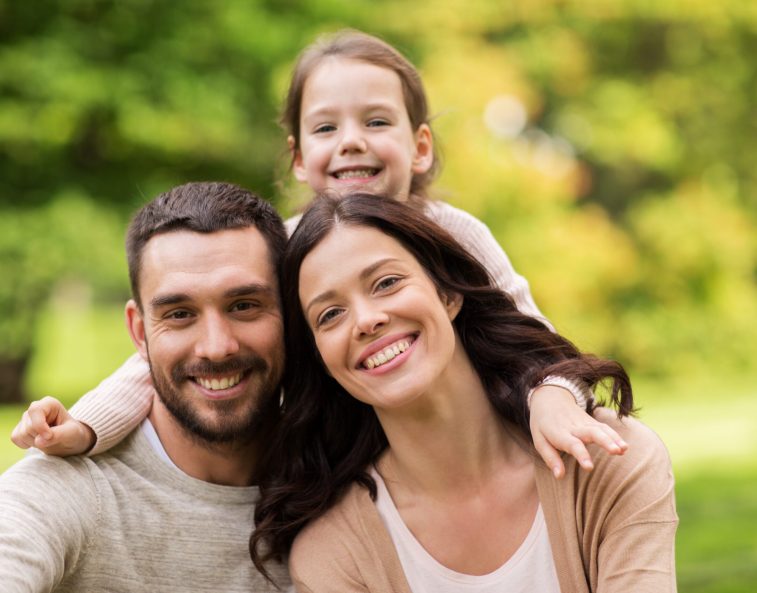 family, parenthood, adoption and people concept - happy mother, father and little girl in summer park